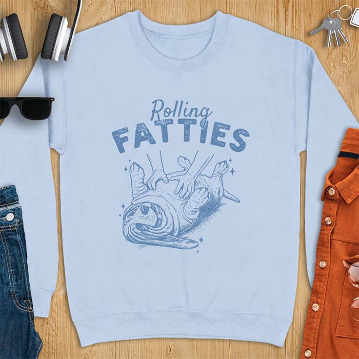 Light Blue sweatshirt with a graphic of a basset hound lying on its back while a pair of hands knead its rolled up folds like dough and the text Rolling Fatties