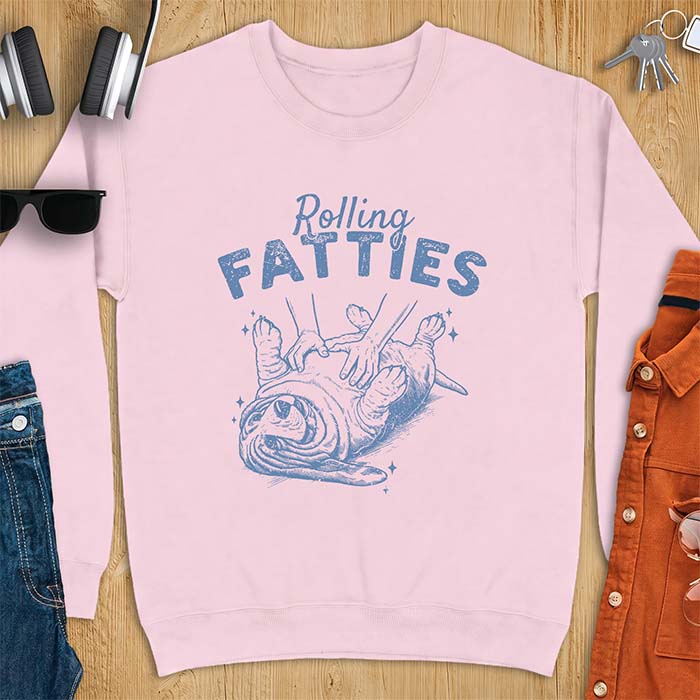 Light Pink sweatshirt with a graphic of a basset hound lying on its back while a pair of hands knead its rolled up folds like dough and the text Rolling Fatties