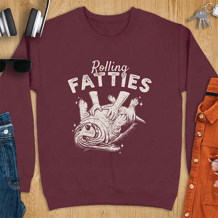Maroon sweatshirt with a graphic of a basset hound lying on its back while a pair of hands knead its rolled up folds like dough and the text Rolling Fatties