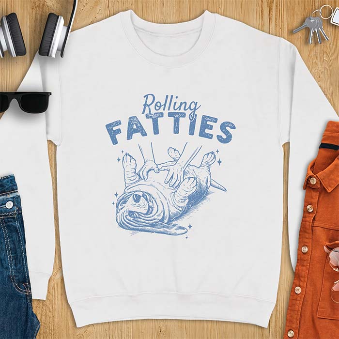 White sweatshirt with a graphic of a basset hound lying on its back while a pair of hands knead its rolled up folds like dough and the text Rolling Fatties