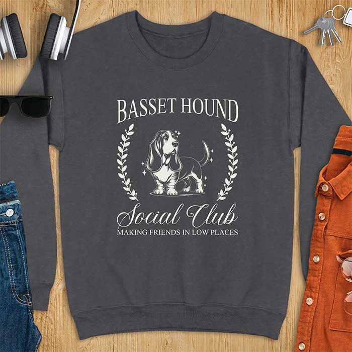 Dark Heather sweatshirt with a vintage crest graphic of a basset hound standing inside a laurel wreath and the text Basset Hound, Social Club and Making Friends In Low Places