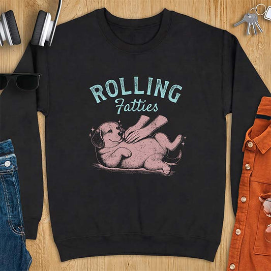 Black sweatshirt with a graphic of a beagle puppy lying on its back getting a belly rub from a hand, paws in the air and sparkles around it, with the text Rolling Fatties printed above