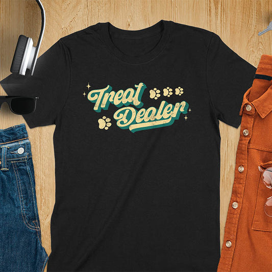 Black t-shirt with Treat Dealer text in retro script typography with green and yellow colors and paw print decorations