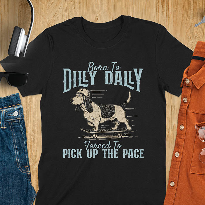 Basset hound wearing helmet on skateboard with Born To Dilly Dally Forced To Pick Up The Pace lettering on black tee