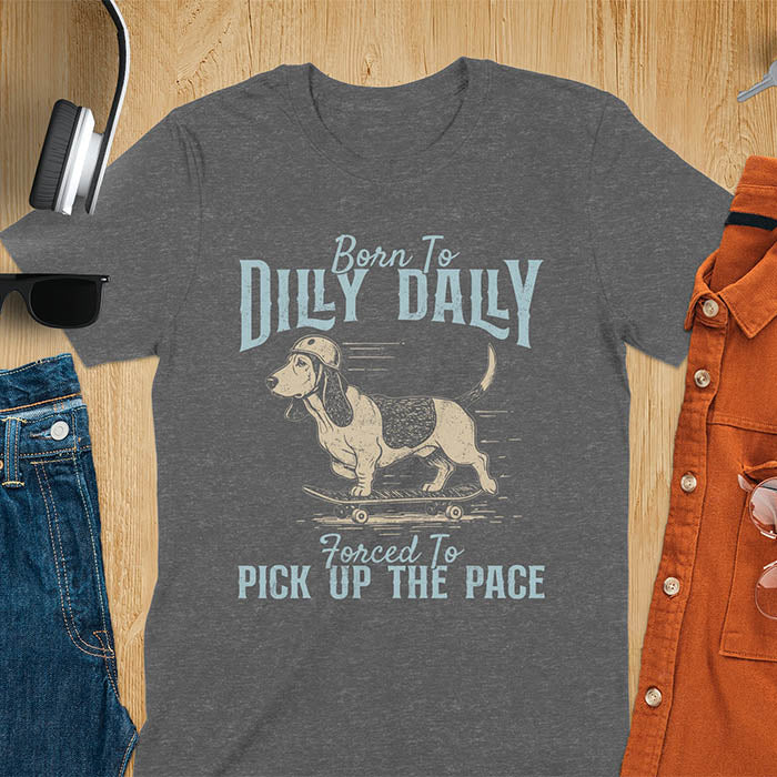 Basset hound wearing helmet on skateboard with Born To Dilly Dally Forced To Pick Up The Pace lettering on dark heather tee