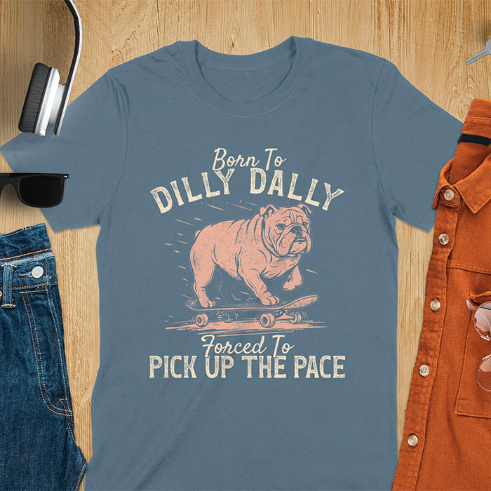 Grumpy bulldog on skateboard illustration with Born To Dilly Dally text and Forced To Pick Up The Pace slogan on indigo blue tee