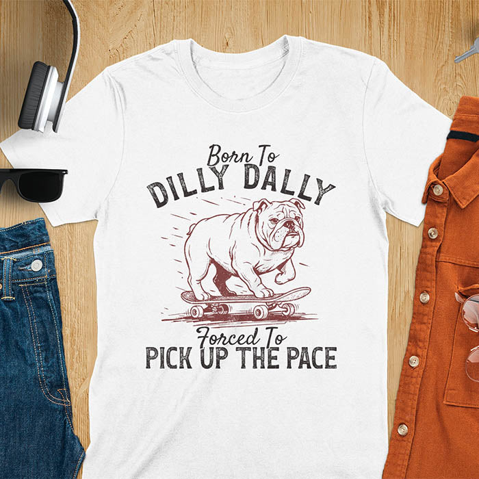 Grumpy bulldog on skateboard illustration with Born To Dilly Dally text and Forced To Pick Up The Pace slogan on white tee