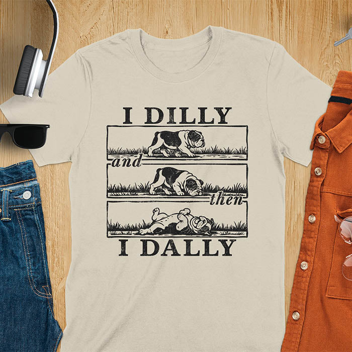 Sand color t-shirt with vintage comic strip graphic of a bulldog walking, rolling, then lying belly-up with text I Dilly and then I Dally