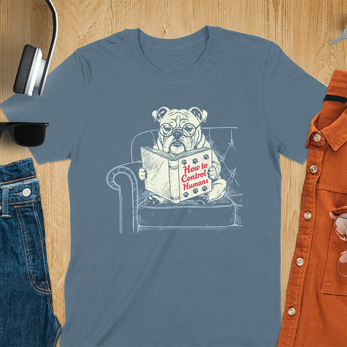 Indigo blue t-shirt with vintage bulldog illustration reading 'How to Control Human' book on couch - retro graphic design with humor