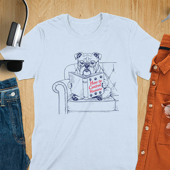 Light blue t-shirt with vintage bulldog illustration reading 'How to Control Human' book on couch - retro graphic design with humor