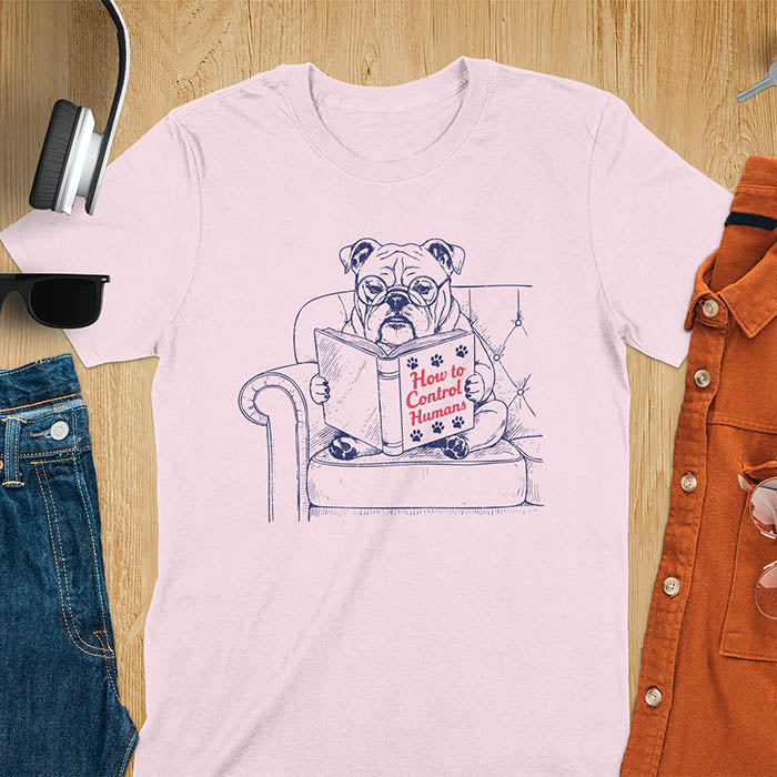 Light pink t-shirt with vintage bulldog illustration reading 'How to Control Human' book on couch - retro graphic design with humor