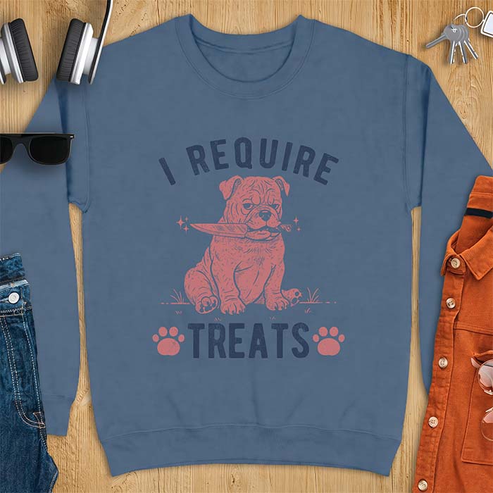 Indigo Blue sweatshirt with a graphic of a deadpan English Bulldog puppy sitting in grass holding a knife in its mouth, with the text I Require Treats and two paw prints