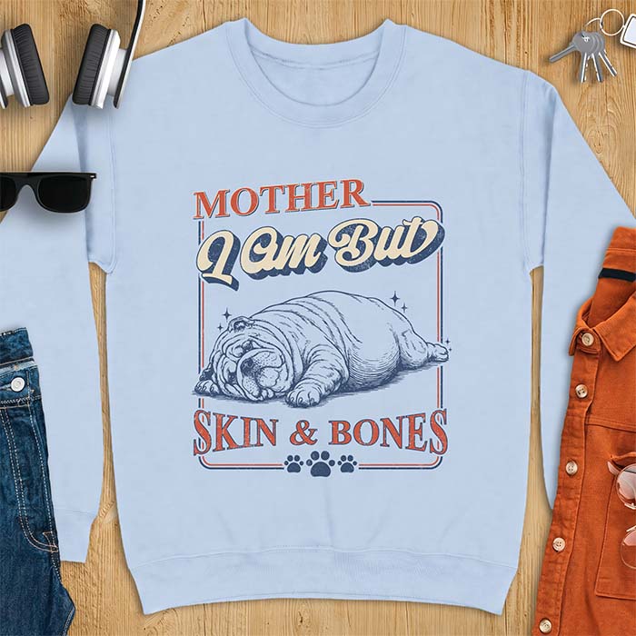 Light Blue sweatshirt with a graphic of an English Bulldog sprawled flat and exhausted, small sparkles floating near its head and the text Mother I Am But Skin & Bones