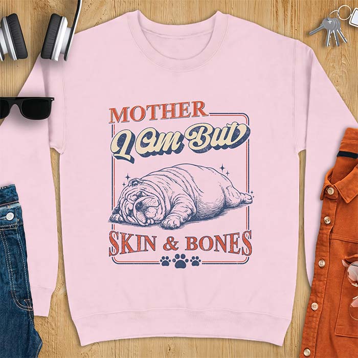 Light Pink sweatshirt with a graphic of an English Bulldog sprawled flat and exhausted, small sparkles floating near its head and the text Mother I Am But Skin & Bones