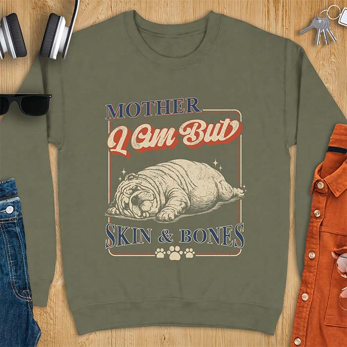 Military Green sweatshirt with a graphic of an English Bulldog sprawled flat and exhausted, small sparkles floating near its head and the text Mother I Am But Skin & Bones