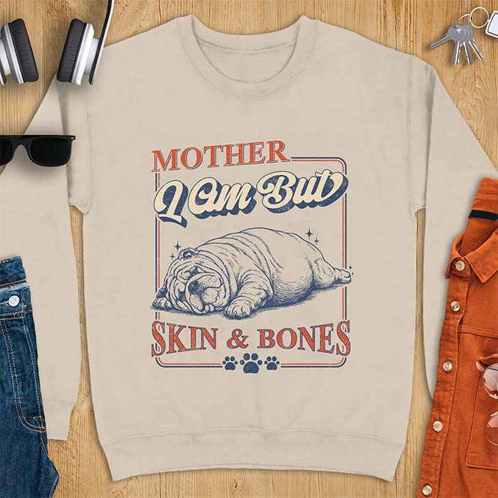 Sand sweatshirt with a graphic of an English Bulldog sprawled flat and exhausted, small sparkles floating near its head and the text Mother I Am But Skin & Bones