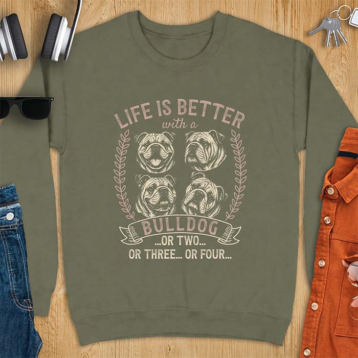 Military Green sweatshirt with a graphic of four vintage-style bulldog head portraits framed by leafy wreaths and a ribbon banner reading Bulldog, featuring the text Life Is Better With A Bulldog, Or Two, Or Three, Or Four.