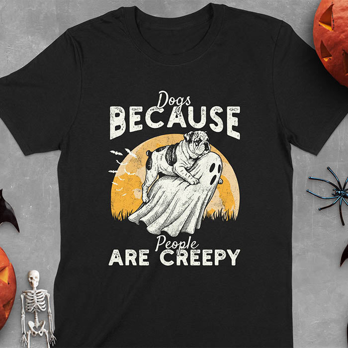 Black Halloween t-shirt featuring bulldog riding piggyback on ghost with moon background and bats, text reads 'Dogs Because People Are Creepy'