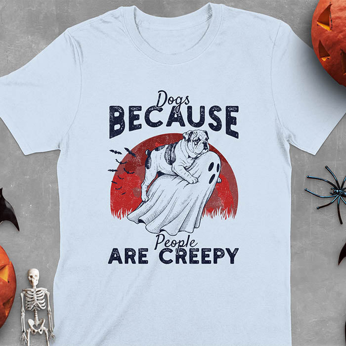 Light blue Halloween t-shirt featuring bulldog riding piggyback on ghost with moon background and bats, text reads 'Dogs Because People Are Creepy'