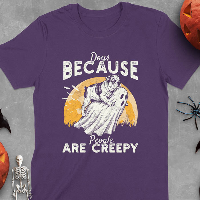 Purple Halloween t-shirt featuring bulldog riding piggyback on ghost with moon background and bats, text reads 'Dogs Because People Are Creepy'