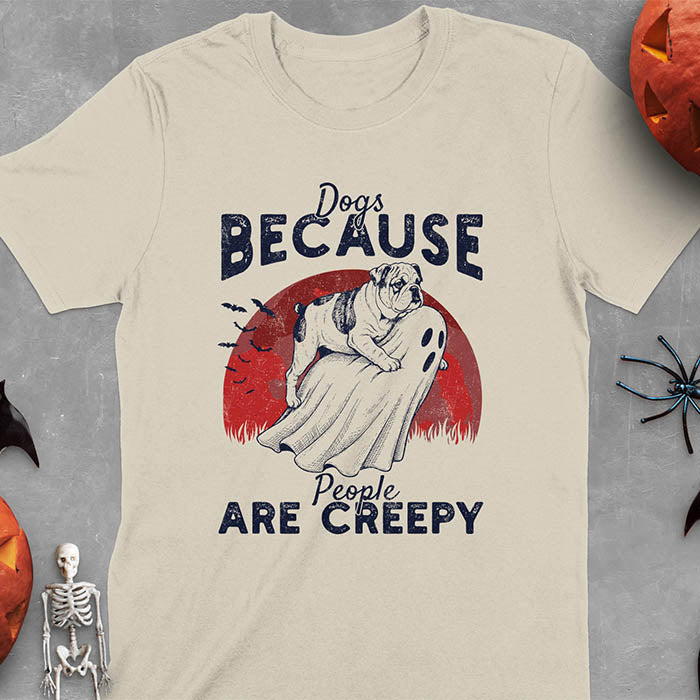 Sand color Halloween t-shirt featuring bulldog riding piggyback on ghost with moon background and bats, text reads 'Dogs Because People Are Creepy'