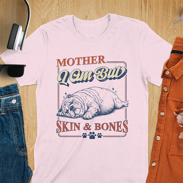 Mother I Am But Skin And Bones text with dramatic sprawled bulldog in pitiful starving pose with vintage retro frame graphic on light pink t-shirt