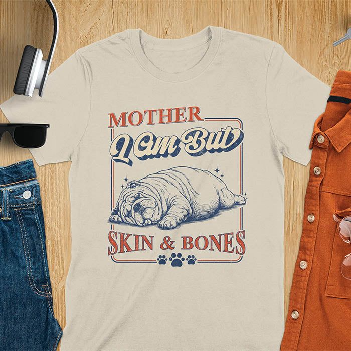 Mother I Am But Skin And Bones text with dramatic sprawled bulldog in pitiful starving pose with vintage retro frame graphic on sand color t-shirt