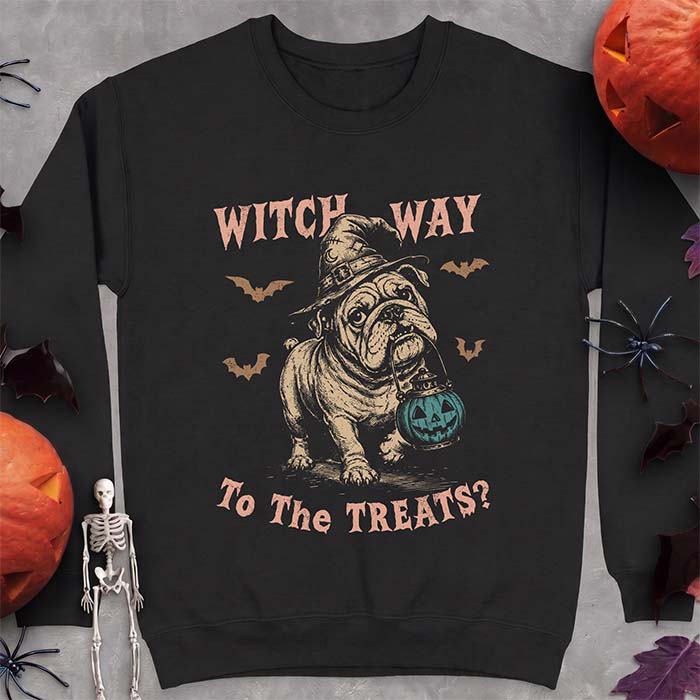 Black sweatshirt with a Halloween graphic of an English Bulldog wearing a patched witch hat carrying a glowing jack-o'-lantern lantern in its mouth with bats flying nearby and the text Witch Way To The Treats?
