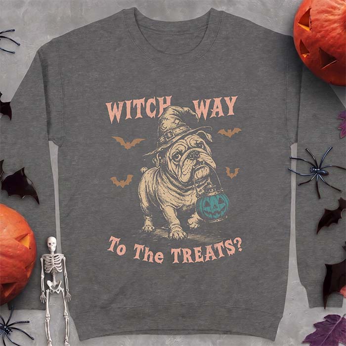 Dark Heather sweatshirt with a Halloween graphic of an English Bulldog wearing a patched witch hat carrying a glowing jack-o'-lantern lantern in its mouth with bats flying nearby and the text Witch Way To The Treats?