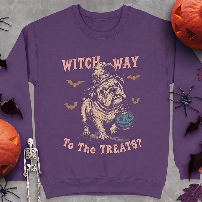 Purple sweatshirt with a Halloween graphic of an English Bulldog wearing a patched witch hat carrying a glowing jack-o'-lantern lantern in its mouth with bats flying nearby and the text Witch Way To The Treats?