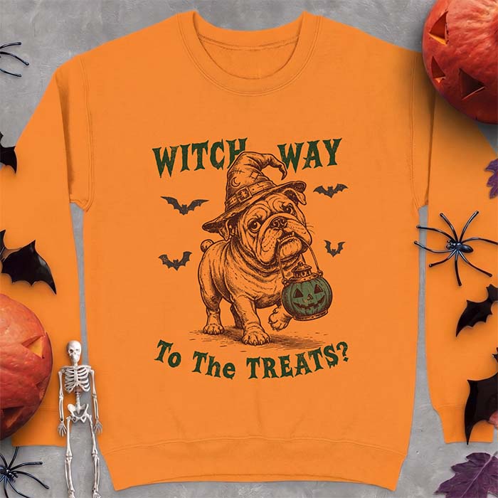 Safety Orange sweatshirt with a Halloween graphic of an English Bulldog wearing a patched witch hat carrying a glowing jack-o'-lantern lantern in its mouth with bats flying nearby and the text Witch Way To The Treats?