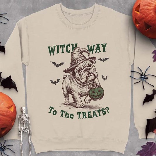 Sand sweatshirt with a Halloween graphic of an English Bulldog wearing a patched witch hat carrying a glowing jack-o'-lantern lantern in its mouth with bats flying nearby and the text Witch Way To The Treats?