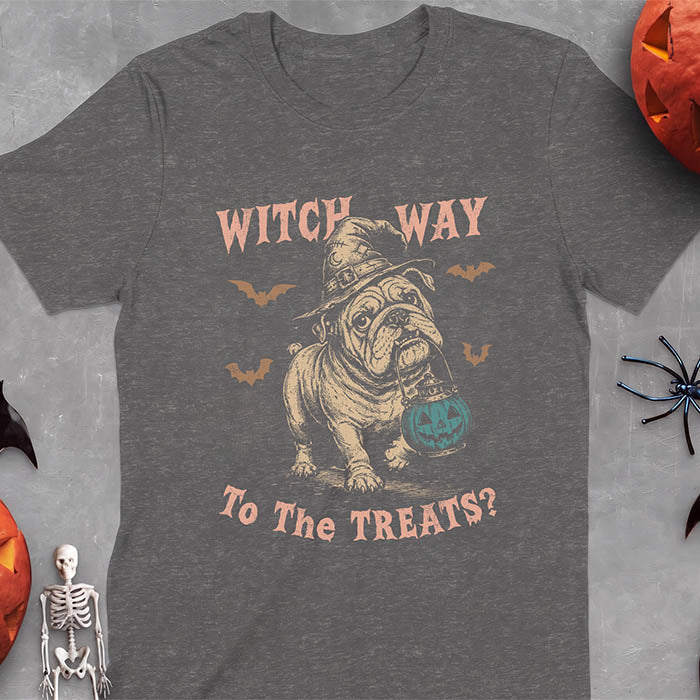 Dark Heather t-shirt with a Halloween graphic of an English Bulldog wearing a patched witch hat carrying a glowing jack-o'-lantern lantern in its mouth with bats flying nearby and the text Witch Way To The Treats?