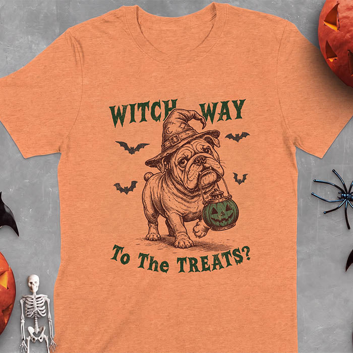 Heather Orange t-shirt with a Halloween graphic of an English Bulldog wearing a patched witch hat carrying a glowing jack-o'-lantern lantern in its mouth with bats flying nearby and the text Witch Way To The Treats?
