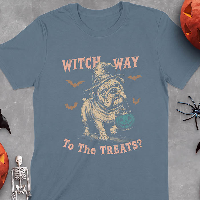 Indigo Blue t-shirt with a Halloween graphic of an English Bulldog wearing a patched witch hat carrying a glowing jack-o'-lantern lantern in its mouth with bats flying nearby and the text Witch Way To The Treats?