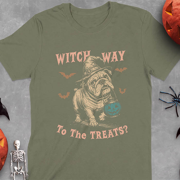 Military Green t-shirt with a Halloween graphic of an English Bulldog wearing a patched witch hat carrying a glowing jack-o'-lantern lantern in its mouth with bats flying nearby and the text Witch Way To The Treats?