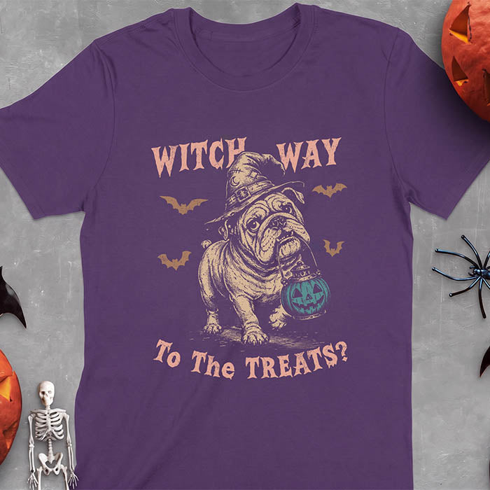 Purple t-shirt with a Halloween graphic of an English Bulldog wearing a patched witch hat carrying a glowing jack-o'-lantern lantern in its mouth with bats flying nearby and the text Witch Way To The Treats?