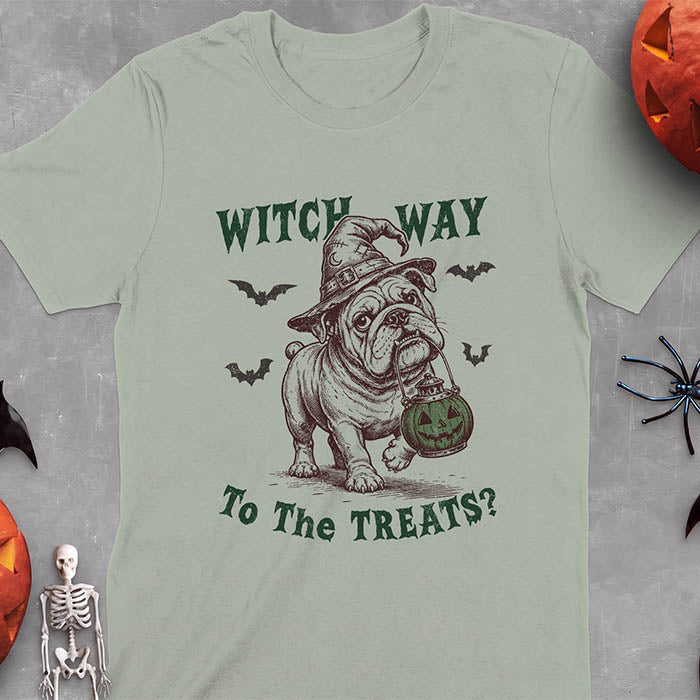 Sage t-shirt with a Halloween graphic of an English Bulldog wearing a patched witch hat carrying a glowing jack-o'-lantern lantern in its mouth with bats flying nearby and the text Witch Way To The Treats?