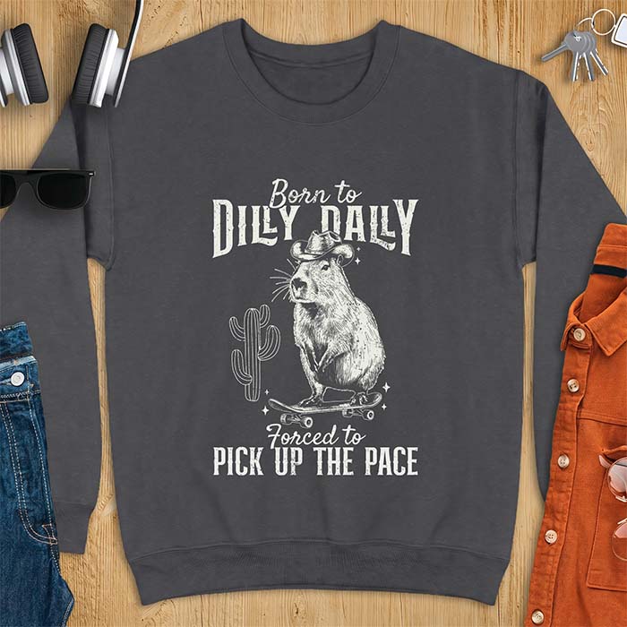 Dark Heather sweatshirt with a graphic of a capybara wearing a cowboy hat balanced on a skateboard beside a cactus, plus the text Born to Dilly Dally and Forced to Pick Up The Pace.