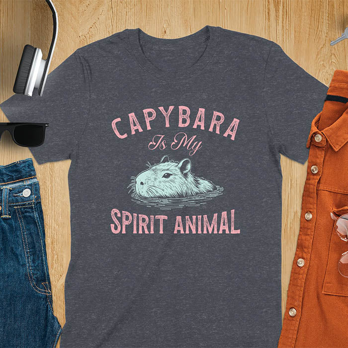 The design features a blue illustration of a capybara's head partly submerged in water and the text "CAPYBARA Is My SPIRIT ANIMAL" in red. This playful and trendy statement captures the calm and social nature of the capybara.