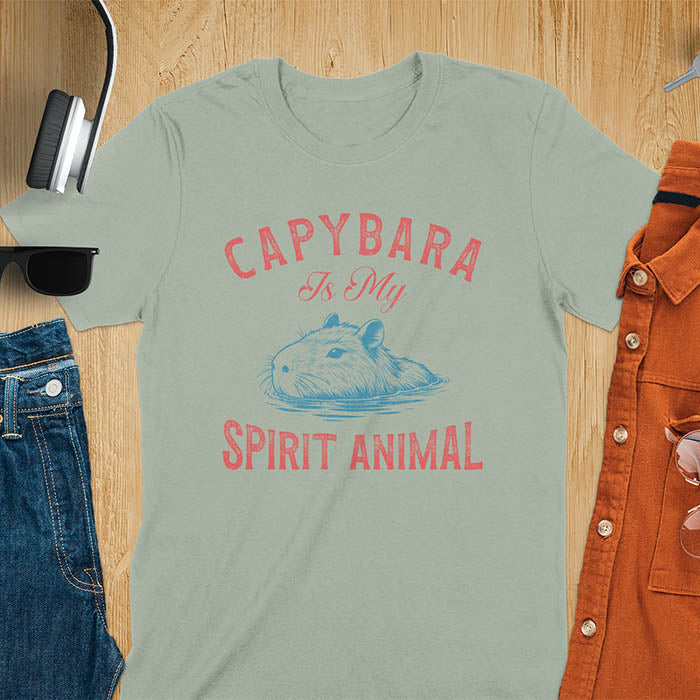The design features a blue illustration of a capybara's head partly submerged in water and the text "CAPYBARA Is My SPIRIT ANIMAL" in red. This playful and trendy statement captures the calm and social nature of the capybara.