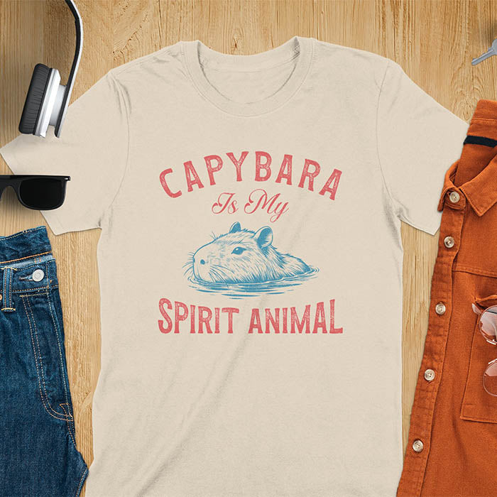 The design features a blue illustration of a capybara's head partly submerged in water and the text "CAPYBARA Is My SPIRIT ANIMAL" in red. This playful and trendy statement captures the calm and social nature of the capybara.