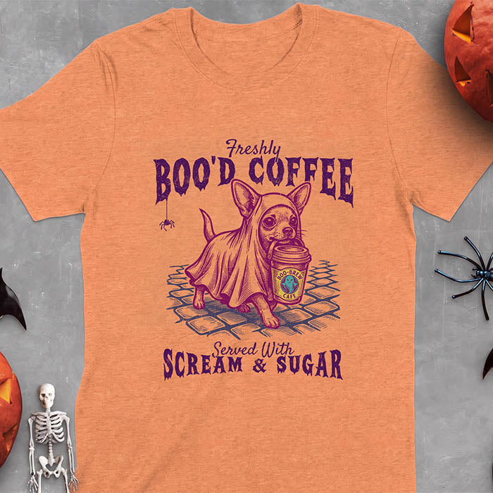 Heather Orange t-shirt with a Halloween graphic of a Chihuahua wearing a ghost costume and holding a coffee cup labeled Boo-Brew Cafe on a cobblestone street with a spider dangling above, plus the text Freshly Boo'd Coffee, Served With Scream and Sugar