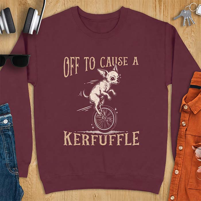 Maroon sweatshirt with a graphic of a chihuahua riding a unicycle with motion lines behind it and the text Off To Cause A Kerfuffle