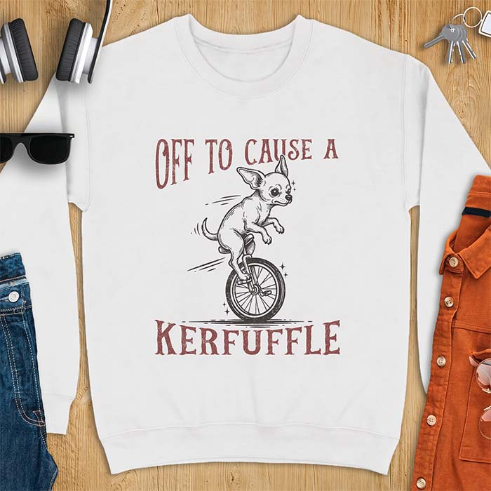 White sweatshirt with a graphic of a chihuahua riding a unicycle with motion lines behind it and the text Off To Cause A Kerfuffle