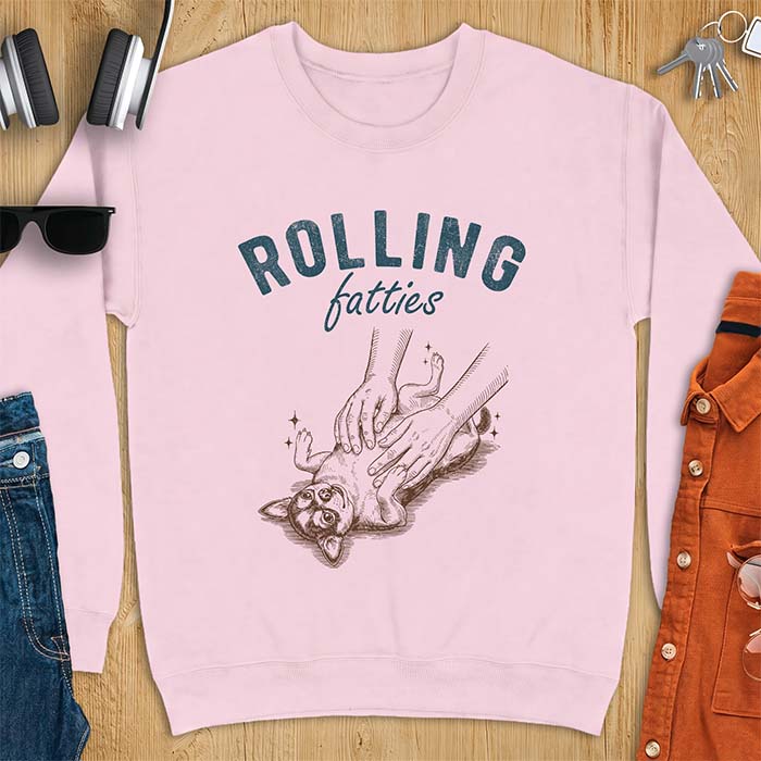 Light Pink sweatshirt with a graphic of a chubby Chihuahua rolled onto its back getting a two-handed belly rub with tiny sparkles around it, above the text Rolling Fatties