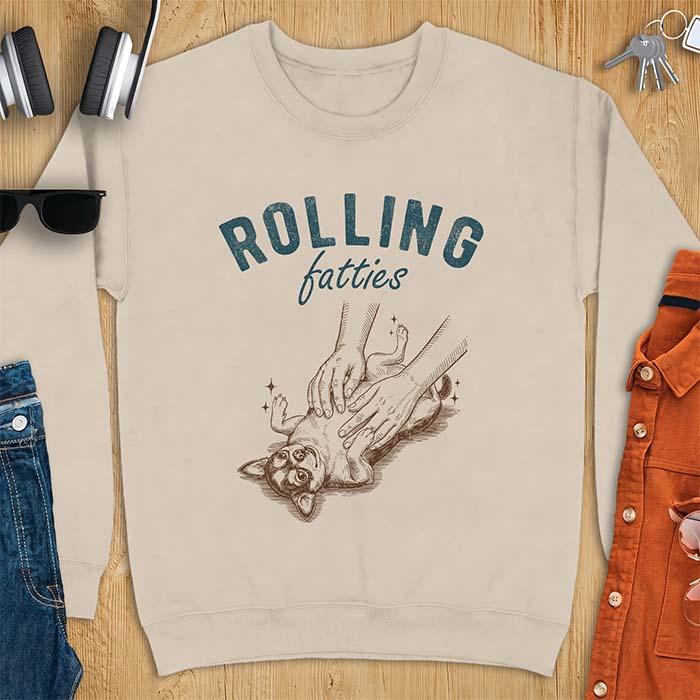 Sand sweatshirt with a graphic of a chubby Chihuahua rolled onto its back getting a two-handed belly rub with tiny sparkles around it, above the text Rolling Fatties