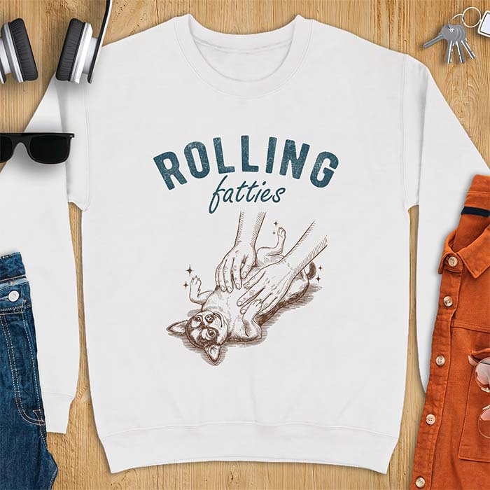 White sweatshirt with a graphic of a chubby Chihuahua rolled onto its back getting a two-handed belly rub with tiny sparkles around it, above the text Rolling Fatties