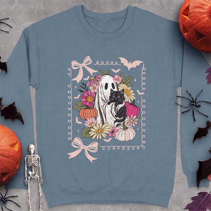 Indigo Blue sweatshirt with a Halloween graphic of a black cat held by a friendly ghost, surrounded by pink and peach florals, pastel pumpkins, bats and black ribbon bows