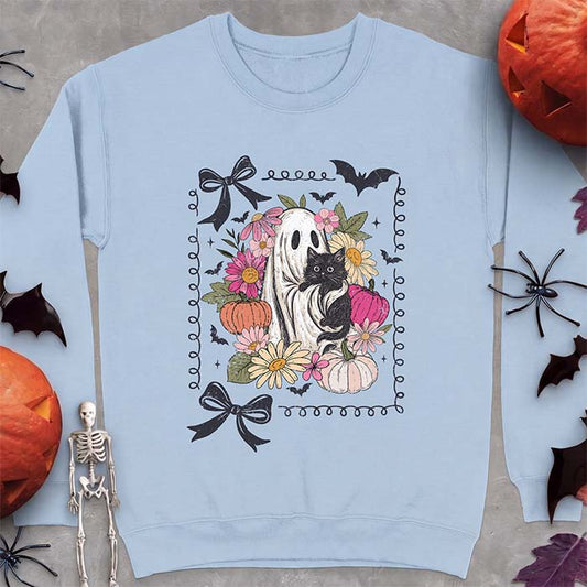 Light Blue sweatshirt with a Halloween graphic of a black cat held by a friendly ghost, surrounded by pink and peach florals, pastel pumpkins, bats and black ribbon bows